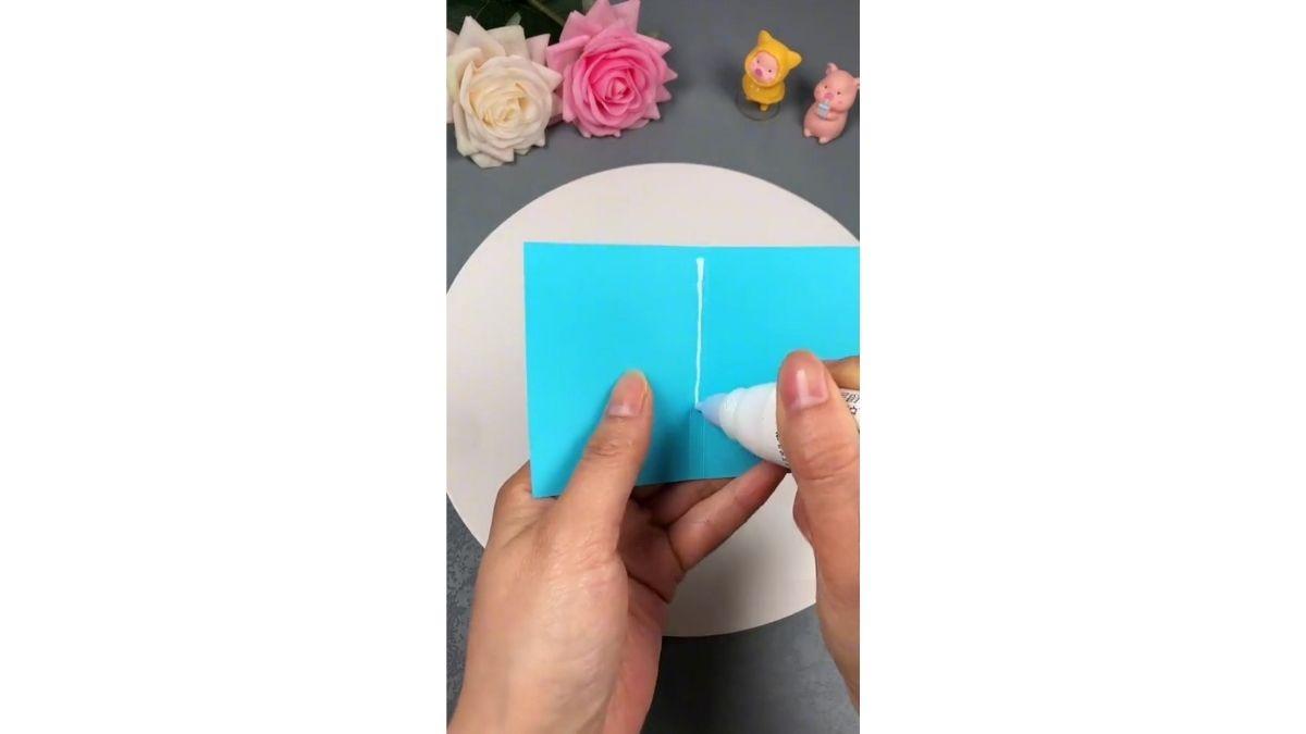 Bôi keo dán vào giữa tờ giấy bìa