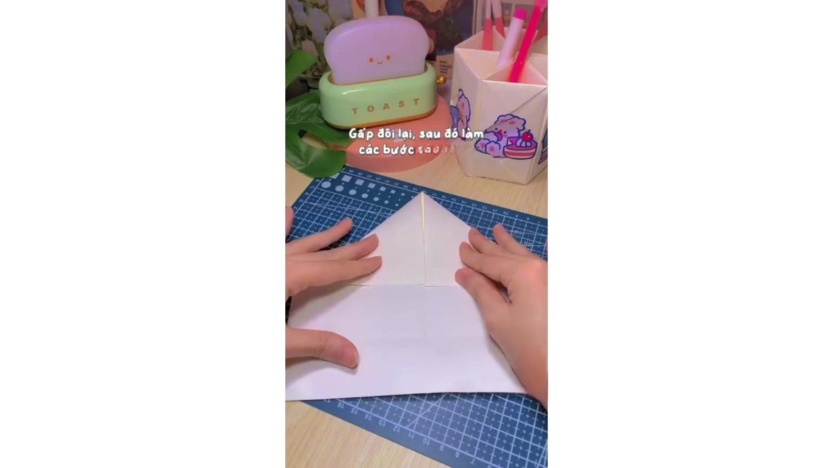 Mở tờ giấy A4 ra và gấp 2 cạnh nửa trên sao cho chạm mép với nếp ở bước đầu